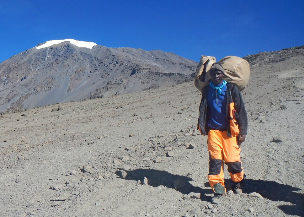responsible travel, Kilimanjaro porter carrying luggage, climb mount kilimanjaro